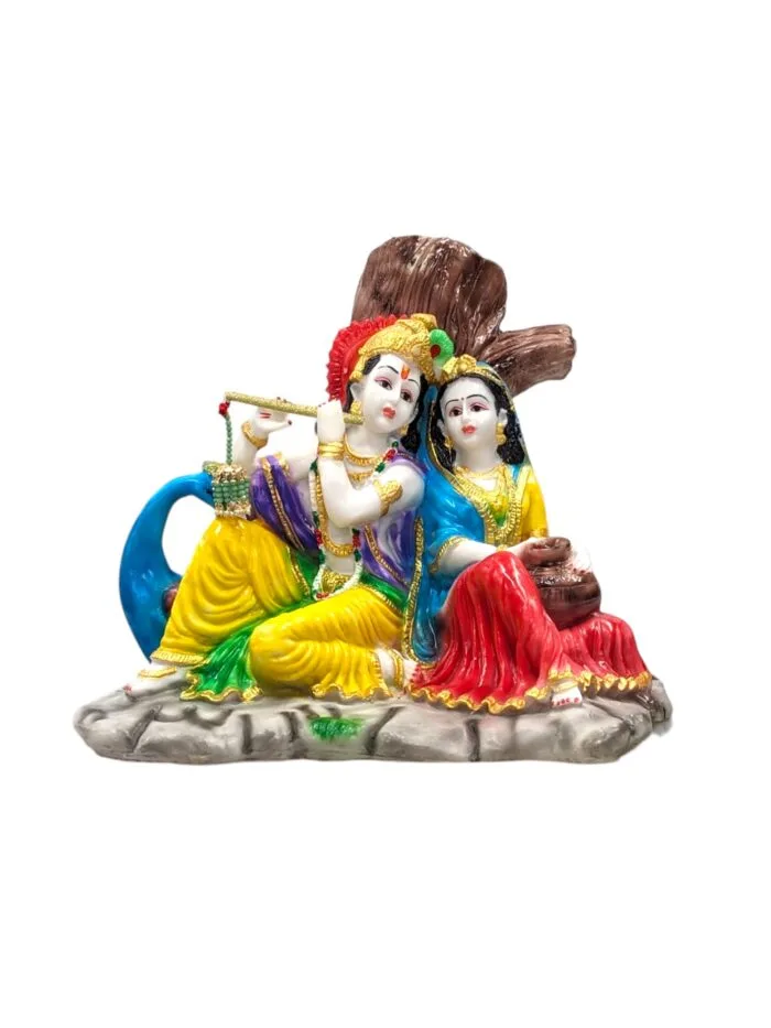 Radha Krishna statue sitting besides each other in front of a tree listening to the blissful tones of Krishna flute