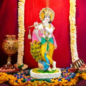 A beautiful Idol of Krishna playing his flute standing along a peacock.