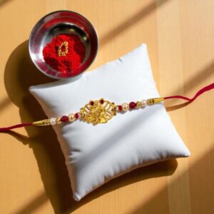 Elegant Radha Krishna Golden Rakhi with kumkum and Indian sweets hamper