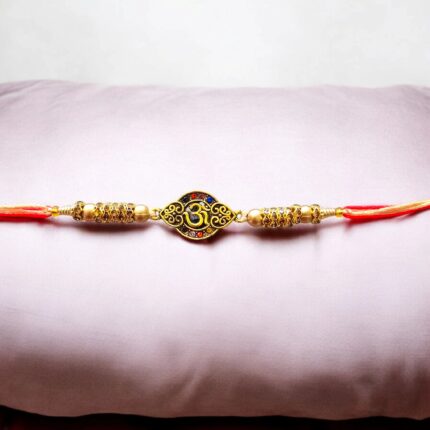 Close-up of Om Rakhi with lustrous red and blue stone detail