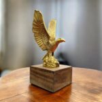 Close-up of detailed brass eagle sculpture showing textured feathers and sharp talons.