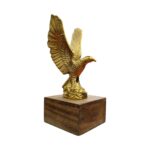 Handcrafted brass flying eagle sculpture on a dark wood base, symbol of freedom and strength.
