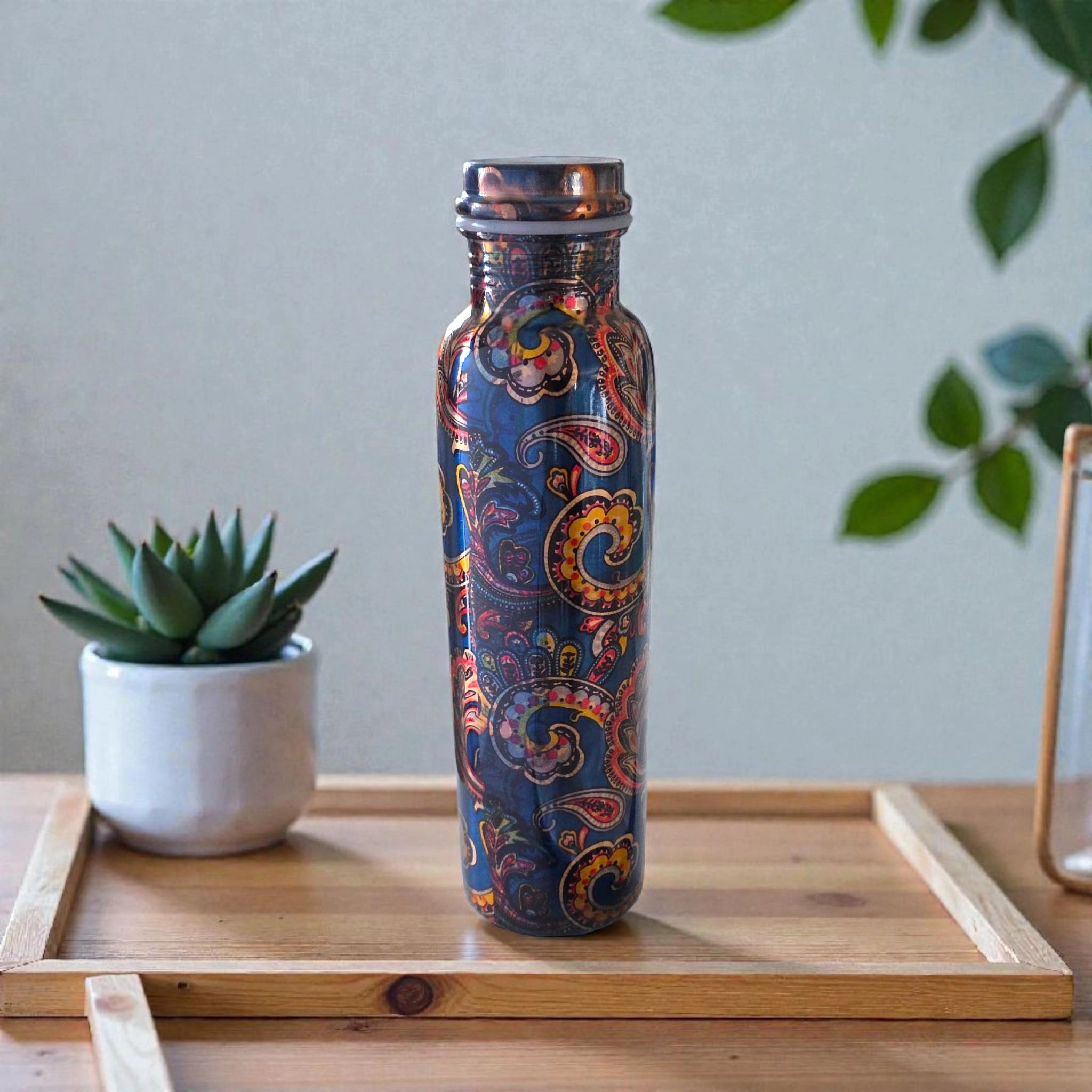 Pure copper water bottle with elegant print Artisan-made pure copper water bottle from India, shown on a wooden table.