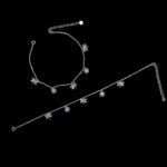 Pair of 925 sterling silver anklets with charms and rhodium finish placed on a black velvet screen