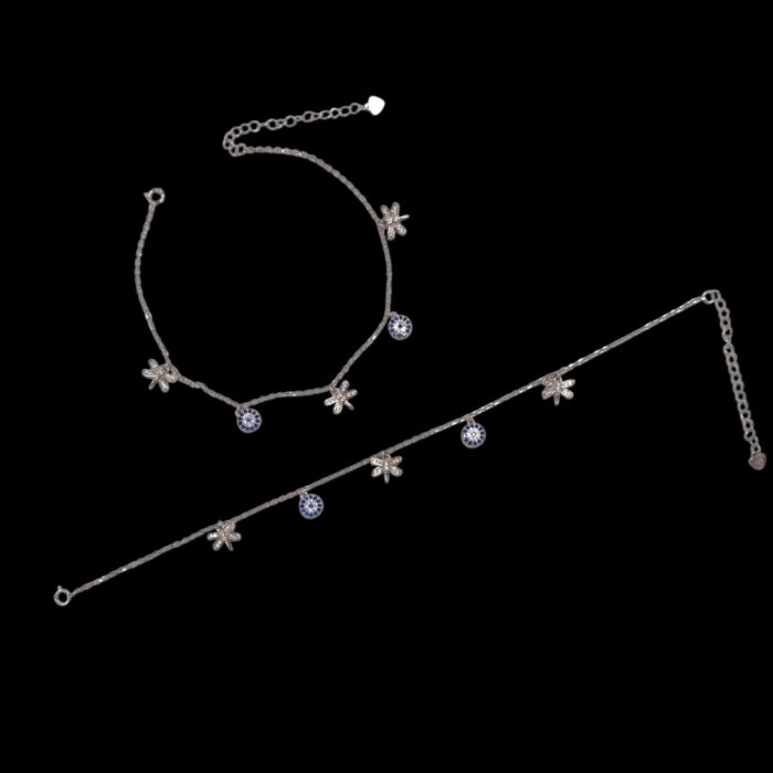 Pair of 925 sterling silver anklets with charms and rhodium finish placed on a black velvet screen