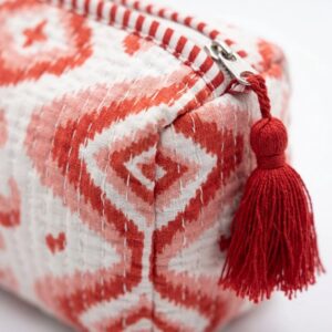 Close-up of red quilted cotton travel pouch showing traditional Indian block print and zipper