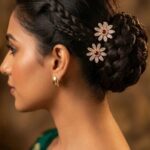 Woman wearing gold plated ruby AD stone flower juda pins in a braided bun with a green silk saree