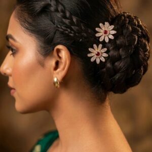 Woman wearing gold plated ruby AD stone flower juda pins in a braided bun with a green silk saree