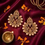 Gehna chandbali earrings styled on maroon silk with marigold petals and brass diya