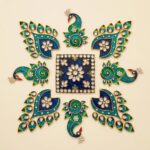 Close-up of teal and emerald peacock metal rangoli pieces with gold-tone trim.