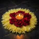 7 inch yellow flower rangoli centrepiece with deep maroon velvet roses and a lit gold filigree tealight, styled on dark marble for Diwali decoration in Canada.