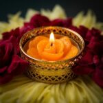 Close up of the removable gold filigree tealight holder and orange rose shaped candle in the flower rangoli diya set, showing it fits a standard tealight.