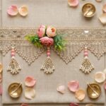 Blush rose mirror toran flat lay with diyas — gold mirror lace, artificial pink roses and faux pearl tassels for wedding door decor