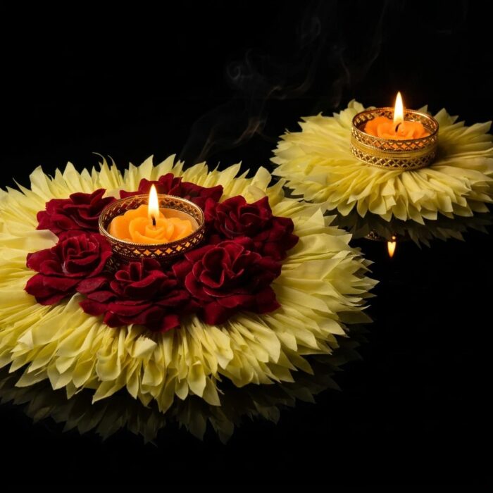7 inch and 4 inch yellow flower rangoli diyas lit on a reflective black surface, showing the size difference between the centrepiece and the smaller pieces.
