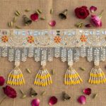 Golden mirror work toran flat lay - glass mirror embroidery, faux pearl garlands and yellow bead latkans for Diwali door decor