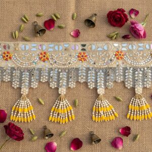 Golden mirror work toran flat lay - glass mirror embroidery, faux pearl garlands and yellow bead latkans for Diwali door decor