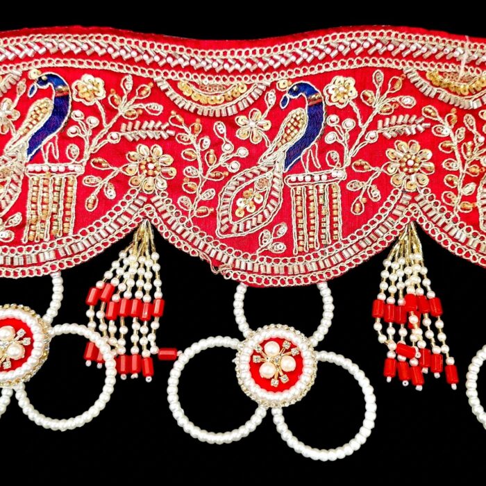 Close up of red gota patti toran peacock embroidery gold zari sequins pearl medallion and red bead tassel