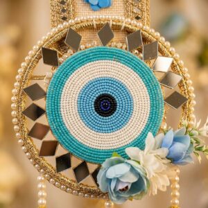 Close-up of hand-beaded evil eye motif in turquoise and blue seed beads, ringed with gold-framed glass mirror diamonds