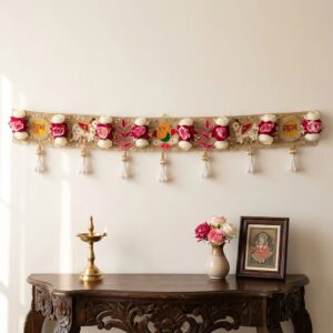 Golden Shubh Labh bandhanwar toran hanging on a wall, 40 inch embroidered door hanging with pink and white roses, pearl tassels, Ganesha and elephant motifs, styled with brass diya for Diwali decor
