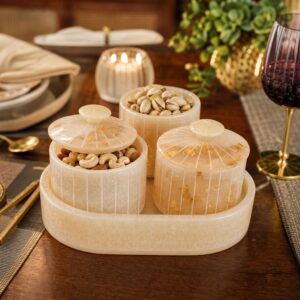 Miraya Cream Ivory resin dry fruit jar set with gold foil flakes — 3 airtight jars on an oval serving tray, filled with almonds and pistachios, styled on a dining table